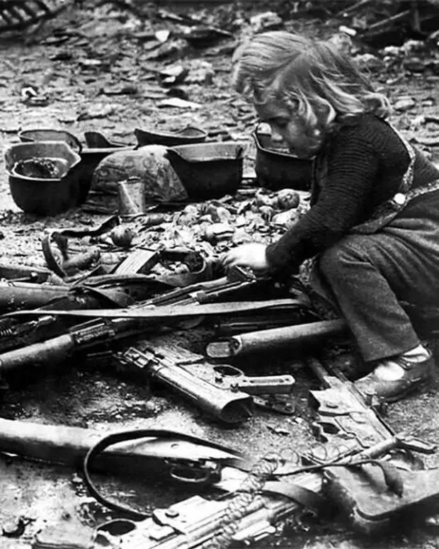 Девочка играет с оружием на улице Берлина. Май 1945 года.