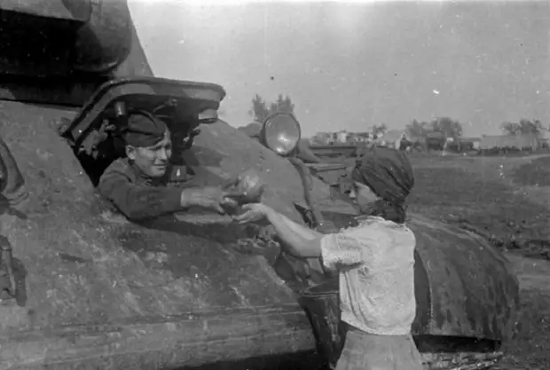 Жительница освобожденного украинского села угощает арбузами механика-водителя танка Т-34, 1943 год.