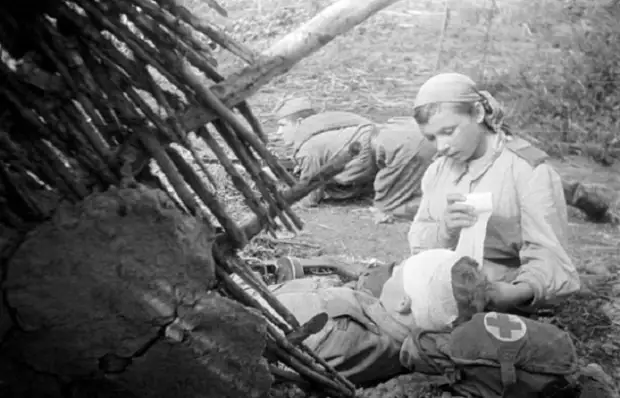 Санинструктор 705-го стрелкового полка старший сержант Пономарева перевязывает раненого в голову младшего лейтенанта  Смирнова, 1943 год.