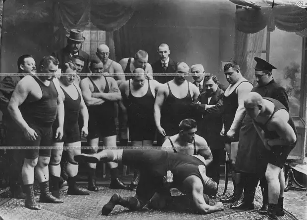Группа участников чемпионата наблюдает за борьбой двух борцов (первый в первом ряду слева стоит И.М.Поддубный