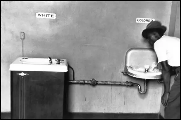 Афро-американец у питьевых фонтанчиков с надписями Для белых и Для цветных