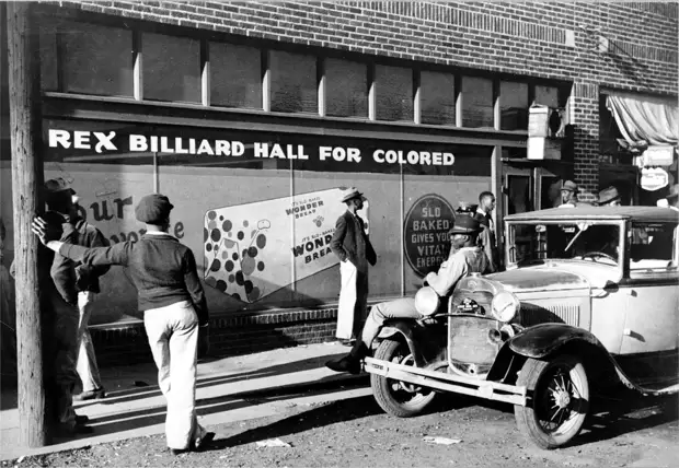 Группа афро-американцев перед входом в бильярдную с надписью Для цветных
