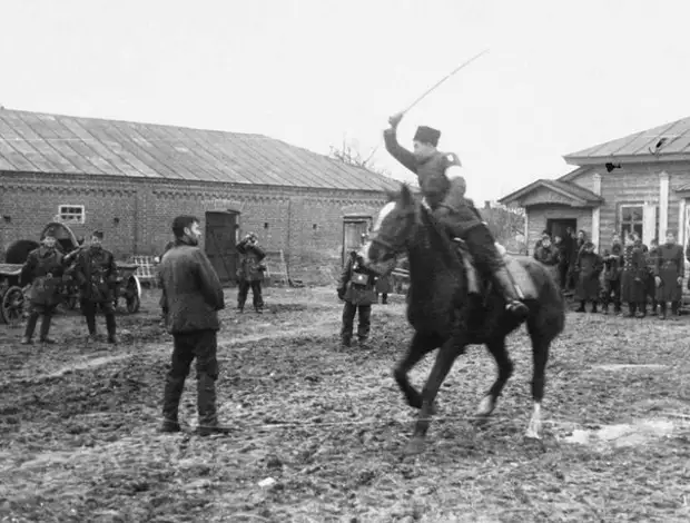 Полицай на потеху венгерским оккупантам рубит шашкой пленных советских партизан. Осень 1941 года, Украина.